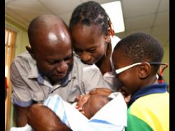 Ricardo Makyn/Chief Photo Editor
Sinclair Hutton caresses his son Sae’breon alongside the child’s mother, Suzett Whyte, and brother, Rudean, at the Denham Town Police Station minutes after he was returned to his family by the Child Protection and Family Services Agency last Friday.