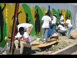 Students of the Edna Manley College of the Visual and Performing Arts participate in a community outreach project, painting a mural on the Rio Cobre Juvenile Correctional Centre’s wall. 