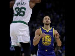 Golden State Warriors’ Stephen Curr (right) follows his shot against the Boston Celtics in the first half of an NBA basketball game on Tuesday, March 5, in Oakland, California.