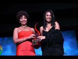 Naomi Cowan (right) receives the breakthrough artiste of the year award from Nadine Sutherland at the Jamaica Reggae Industry Association 2019 honours awards, held at the Little Theatre on Tuesday.