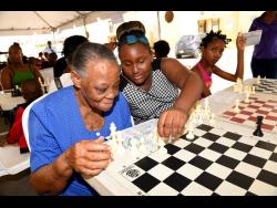 Ricardo Makyn photos
Leanora Stewart, 73, a resident of Portia Simpson Miller Meadows, learns chess from 12-year-old Daisha Fraser. The occasion was the National Housing Trust’s Social Development Department’s introduction to chess initiative, a community intervention targeting youth, which started on Ash Wednesday. Members of the National Chess Club assisted with the teaching of the game.  