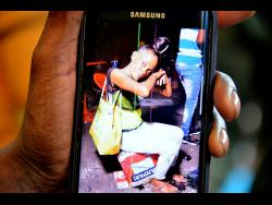 Credit: Kenyon Hemans An associate of Charmaine ‘Pat’ Brown shows a photo of the deceased.