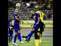 Jamaica’s Cory Burke (right) rises above two Cayman Islands defenders to win a header during the team’ CONCACAF Nations League game at the National Stadium.