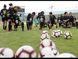 Members of Jamaica’s Reggae Girlz squad stretch before the start of a training session at the National Stadium.