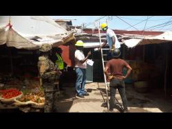 Workmen employed to the Jamaica Public Service Company Limited carry out disconnections on dozens of shops and stalls within the Charles Gordon Market in Montego Bay, on Monday.
