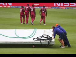 West Indies players go off the field as groundsmen bring on the covers after rain stopped play during the Cricket World Cup warm-up match between West Indies and South Africa in Bristol, England, yesterday.