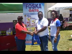 Claudette Anderson receives a gift bag from Jamaica’s most successful cricket captain Tamar Lambert, after a bowl-off at the  SDC/ Wray and Nephew National Community T20 Cricket competition at the Dumfries Oval in St James last Sunday, looking on is a representative from Foska Oats. 