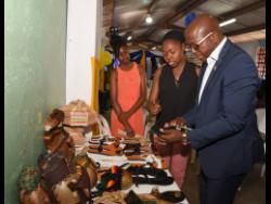 Contributed
Chantal Lewis (centre) shows a pair of her sandals to Senator Pearnel Charles Jr, at the recent launch of the Palmers Cross Community Development Committee in Clarendon. Looking on is her sister, Ca-Deiva Clarke.