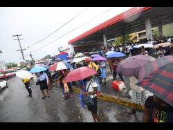Commuters are stranded in the rain on North Odeon Avenue yesterday due to the withdrawal of services by drivers of the Jamaica Urban Transit Company.