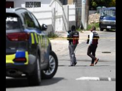 Police process the scene on Nelson Road, St Andrew, where a man from Greenwich Farm was killed by gunmen yesterday.