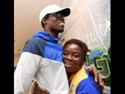 World Championships long jump gold medallist Tajay Gayle is embraced by  Shanikie Osbourne, the head coach at his alma mater Papine High, after he arrived home last night.