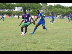 William Knibb Memorial High School’s Deano Thomas (left) is tracked by Cedric Titus High School’s Javel Green in their ISSA/WATA DaCosta Cup Group C encounter at William Knibb on September 17. 