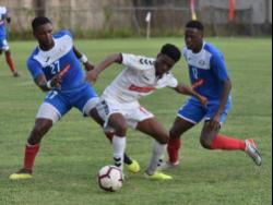 Trey Bennett (centre) from UWI FC tries to go between the Portmore United pair of Sheldon McKoy (left) and Venton Evans (right) during their Red Stripe Premier League football match  at the Spanish Town Prison Oval yesterday.
