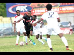 
 Kemar Seivwright of Molynes United FC (second left) comes under immense pressure from Arnett Gardens’ Kimani Arbouine (left) and Paul Wilson  during a Red Stripe Premier League  encounter at the Drewsland Stadium on Sunday, September 22.