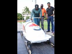 Bobsledder Carrie Russell (left)  shows off her pushing skills to Denzil Wilks (centre), general manager of the Sports Development Foundation (SDF), and Christian Stokes (right), president of the Jamaica Bobsleigh and Skeleton Federation, during a training session at G.C. Foster College yesterday.