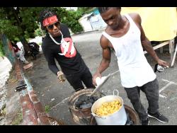 Savage’s childhood friend, Kemar Smith, aka ‘Famo’, checks on the pot while the deejay looks on.