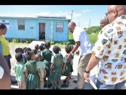 Member of Parliament for Clarendon South East Rudyard Spencer (third right) directs students to view the newly installed solar panels at the St Peter’s Basic School.