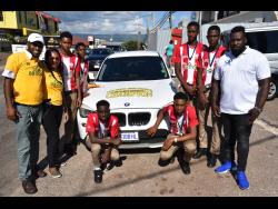 Carlington Sinclair (left) and wife Marsha (second left) show their allegiance to their alma mater BB Coke High with the decorations on their car. Looking on are Patrick Sappleton (right), CEO of SAP Sports, with members of the Ben Francis Cup winning team.