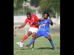 UWI FC’s  Ryan Miller (left) attempts a shot at goal while under pressure from Dunbeholden’s Shevan James during the  Red Stripe Premier League encounter at the UWI Bowl last Sunday. The game ended 0-0.