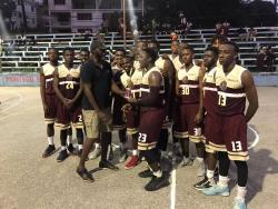 Elfraito Remekie, Jamaica Basketball coordinator, handing over  the championship trophy to members of the  Herbert Morrison Technical High School Under-19 team at the Montego Bay Cricket Club Court yesterday. Herbert Morrison won 74-58 over York Castle. 