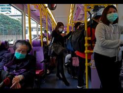 People wear protective face masks on a bus in Hong Kong on Tuesday. Hong Kong reported its first death from coronavirus, a man who had travelled from the mainland city of Wuhan that has been the epicentre of the outbreak.