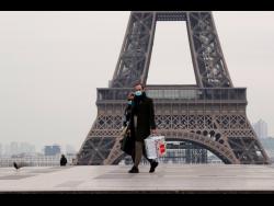 A masked couple walks on the empty Trocadero next to the Eiffel Tower, in Paris, France.