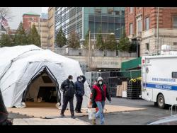 Medical and construction workers are seen at the site of a makeshift morgue that was built outside a hospital in New York on Wednesday. 