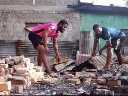 Marcel Gayle (right), head coach of Waterhouse FC, helps his player Akeem Chambers (left) clear rubble from the site where his house once stood, as fire destroyed the young footballer’s home on Saturday.