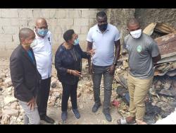 Minister of Sports Olivia Grange (third left) in discussion with Akeem Chambers (right), Reggae Boyz head coach Theodore Whitmore (second right), Jamaica Football Federation president Michael Ricketts (second left) and Mayor of Kingston Delroy Williams in Olympic Gardens yesterday. The group visited the burnt-out house of Akeem Chambers and his brother Tafari. Grange said the Government would play a big role in helping to rebuild the house. 