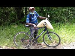 Huecent Spencer, 87, farmer  from Kept district in St Elizabeth, makes his way to his farm after buying a bag of fertiliser.
