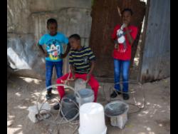 The boys (from left) Shevon, Anthone and Anthony Jackson have captured the attention of strangers and community members with their daily ‘services’ held at their gate.