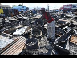 This man sifts through the rubble of the latest fire at Rae Rae Market early Tuesday morning.