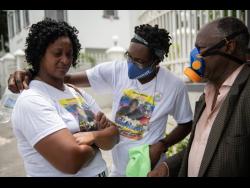 Credit: Gladstone Taylor Yanike Crosdale (left), mother of the late Jevaughn Duhaney, is consoled by Leon Duncan (centre) as they wait for Duhaney’s autopsy to be done at the House of Tranquillity Funeral Home in Kingston yesterday. Looking on is Dr Jephthah Ford.