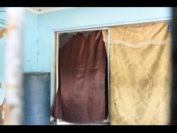 Makeshift curtains are used to cover glass doors of a St Andrew house where residents say gay sex workers operate a brothel. 