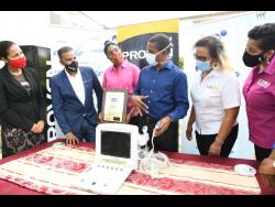 Chief Medical Officer at the Sir John Golding Rehabilitation Centre, Dr Rory Dixon (third right), explains the use of the portable ultrasound machine to  (from left) Latoya Aquart-Foster, CHASE project manager; Johann Heaven, CEO, Proven Wealth; Kecia Taylor, past services director, Rotary Club of St Andrew North; Lori Chuck, past president, Rotary Club of St Andrew North; and Denise Harris, chief marketing officer, C&WJ Credit Union, at the presentation of the equipment to the centre on July 3.