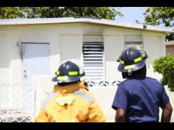 
Firemen look at a house in Bridgeport, St Catherine, where Karen Nugent died in a blaze yesterday.
