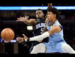 In this March 10, 2020 file photo, Memphis Grizzlies guard Ja Morant (right) passes the ball as Orlando Magic centre Mo Bamba (5) defends during the first half of an NBA basketball game in Memphis.