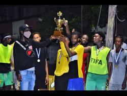 Photo by Anthony Minott 
Tower Hill Strikers celebrate after winning the inaugural Memorial Cup with main organiser Rohan Reid, also known as Young Wild Apache (left).