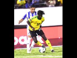Shamar Nicholson dribbles ahead of Honduran player Emilio Izaguirre  in their Concacaf Gold Cup match at the National Stadium last year.