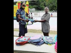 Kid Kurup hands over a school bag to a resident of Standpipe.
