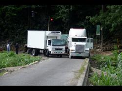 The driver of a small truck navigates his way past the disabled vehicle.