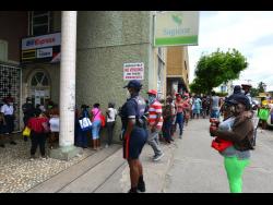 Persons waiting to get inside a Western Union outlet in Spanish Town in April.