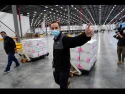 A worker gives a thumbs up while transporting boxes containing the Moderna COVID-19 vaccine to the loading dock for shipping at the McKesson distribution centre in Olive Branch, Mississippi, yesterday. It is expected to be given out starting today. The Pfizer and BioNTech vaccine was rolled out last week.
(AP Photo/Paul Sancya, Pool)