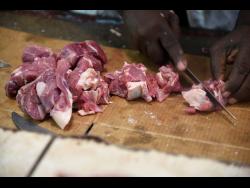 Goat meat being prepared for a customer at the meat market in Cross Roads, Kingston, yesterday.