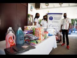Dixon Foundation Assistant Public Relations Officer Romaine Atkinson (right), and Haye Foundation founder Trudy-Ann Haye (left), hand over necessities to the senior supervisor at Mustard Seed Communities, Camille Bromfield, at the Mustard Seed Children’s Home in Olympic Gardens, St Andrew, on Monday.