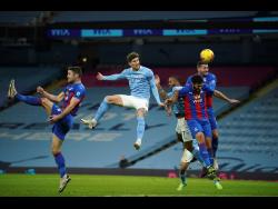 Manchester City’s John Stones (centre), heads the ball to score his side’s opening goal during an English Premier League football match between Manchester City and Crystal Palace at the Etihad Stadium in Manchester, England,  yesterday.