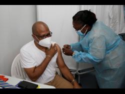 Olufunke Adetola (right), public health nurse for Clarendon, administered the COVID-19 vaccine to St Andrade Sinclair, CEO of the May Pen Hospital.