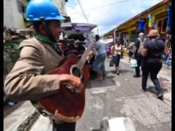 Roydell Edwards plays his guitar and sings outside the Brown’s Town market in St Ann.
