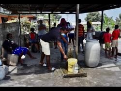 People collect water not contaminated by volcanic ash after the eruption of the La Soufriere volcano in Wallilabou, on the western side of the Caribbean island of St Vincent and the Grenadines, on Monday.