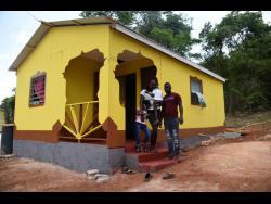 Lemaya Webb (right) with his family in front of their new home, built with the assistance of Nicholas Clarke, in the New Building area of St Elizabeth.